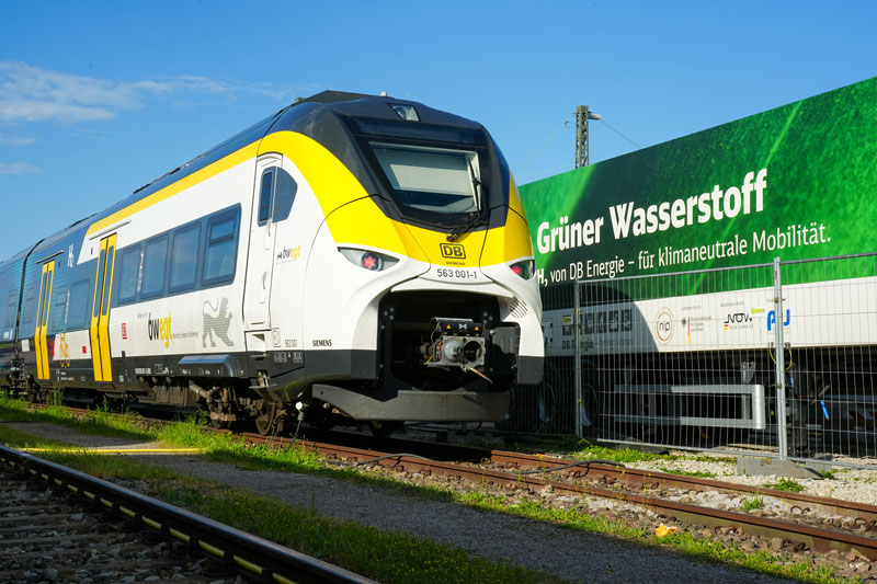 Regionalzug aus Baden-Würtemberg neben Container mit "Grüner Wasserstoff" Aufschrift