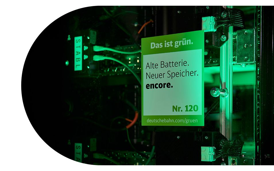 „Das ist grün.“-Siegel des DB-Konzerns klebt auf Plexiglasscheibe von Batteriespeicher von encore | DB. 