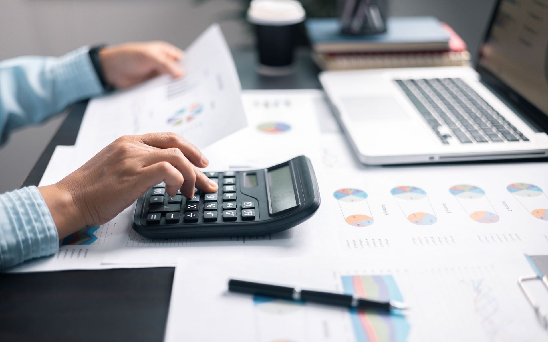 Nahaufnahme der Hand einer Person, die etwas in einen Taschenrechner eintippt.