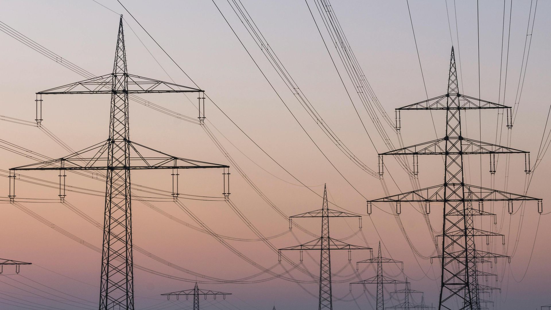 Mehrere Strompfeiler und Hochspannungsleitung vor Abendhimmel.
