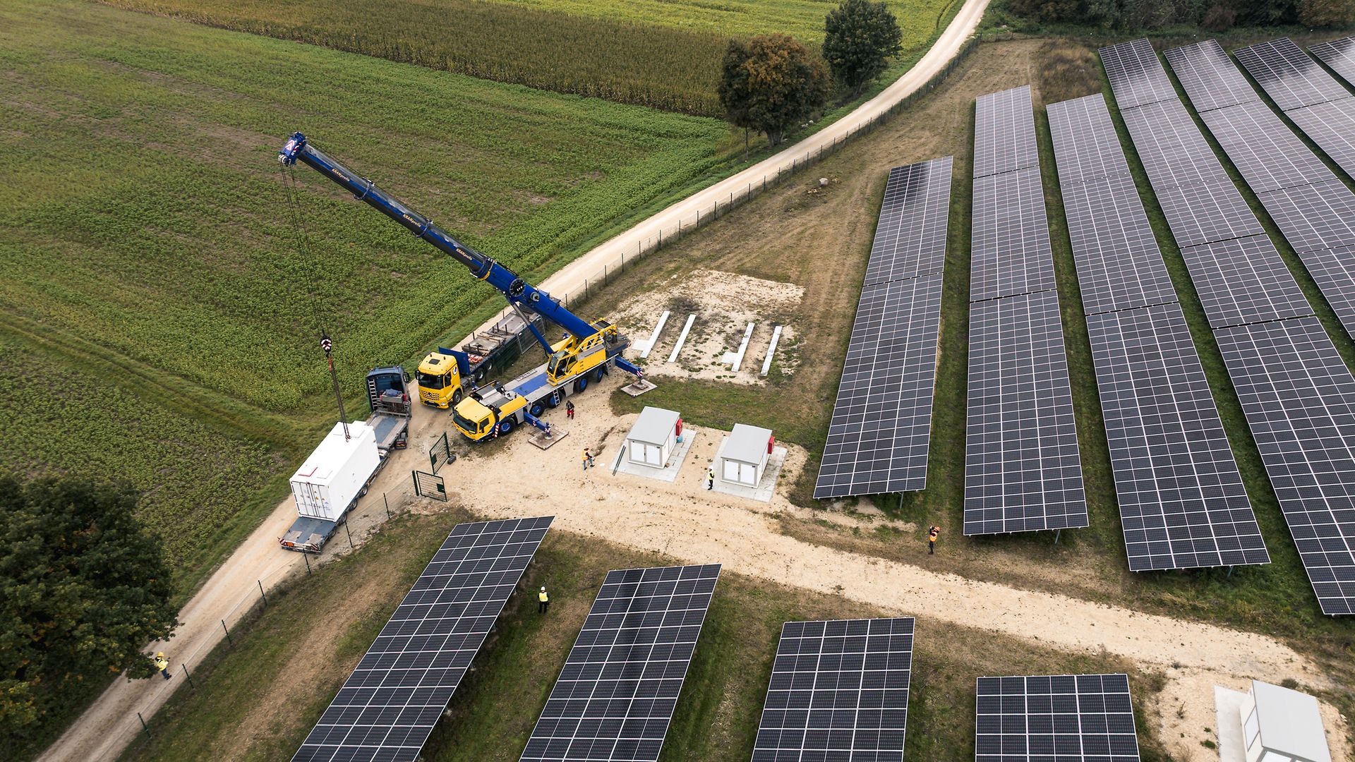 Luftaufnahme des Solarparks von EnBW in Aach, Anlieferung Batteriespeicher, 2 LKWs, 1 Kran, 2 kl. Gebäude, Mitarbeitende